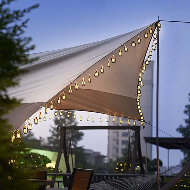 Solar powered retro kerosene string lights glowing on a camping tent at night
